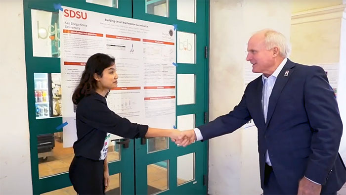 A SDSU Joint Doctoral Program student in Environmental Engineering shakes hands with a SDSU community member