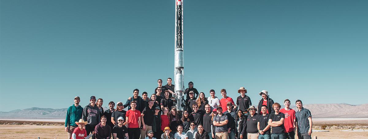 Students standing in front of rocket