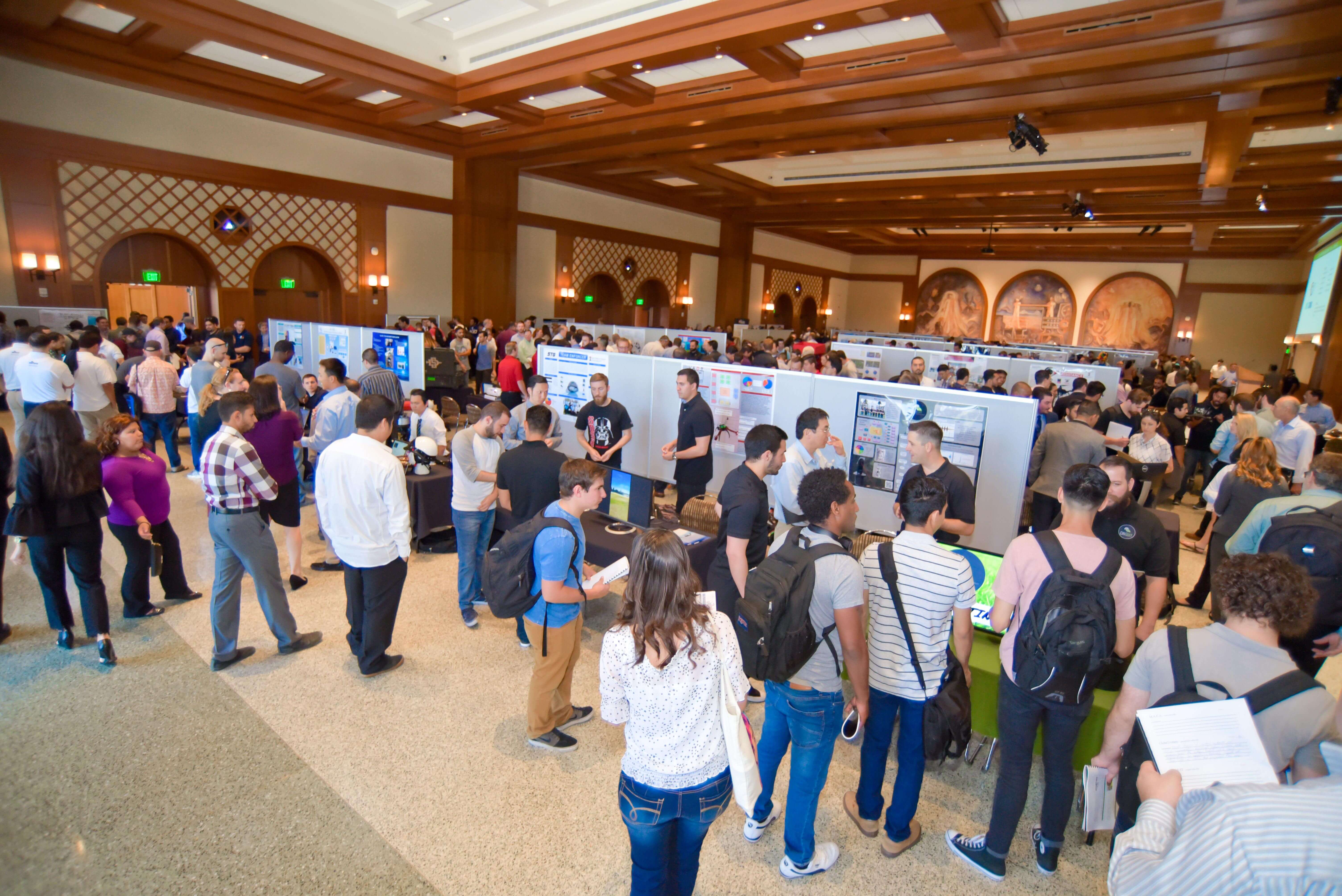 Students and industry professionals looking at student projects in Montezuma Hall.