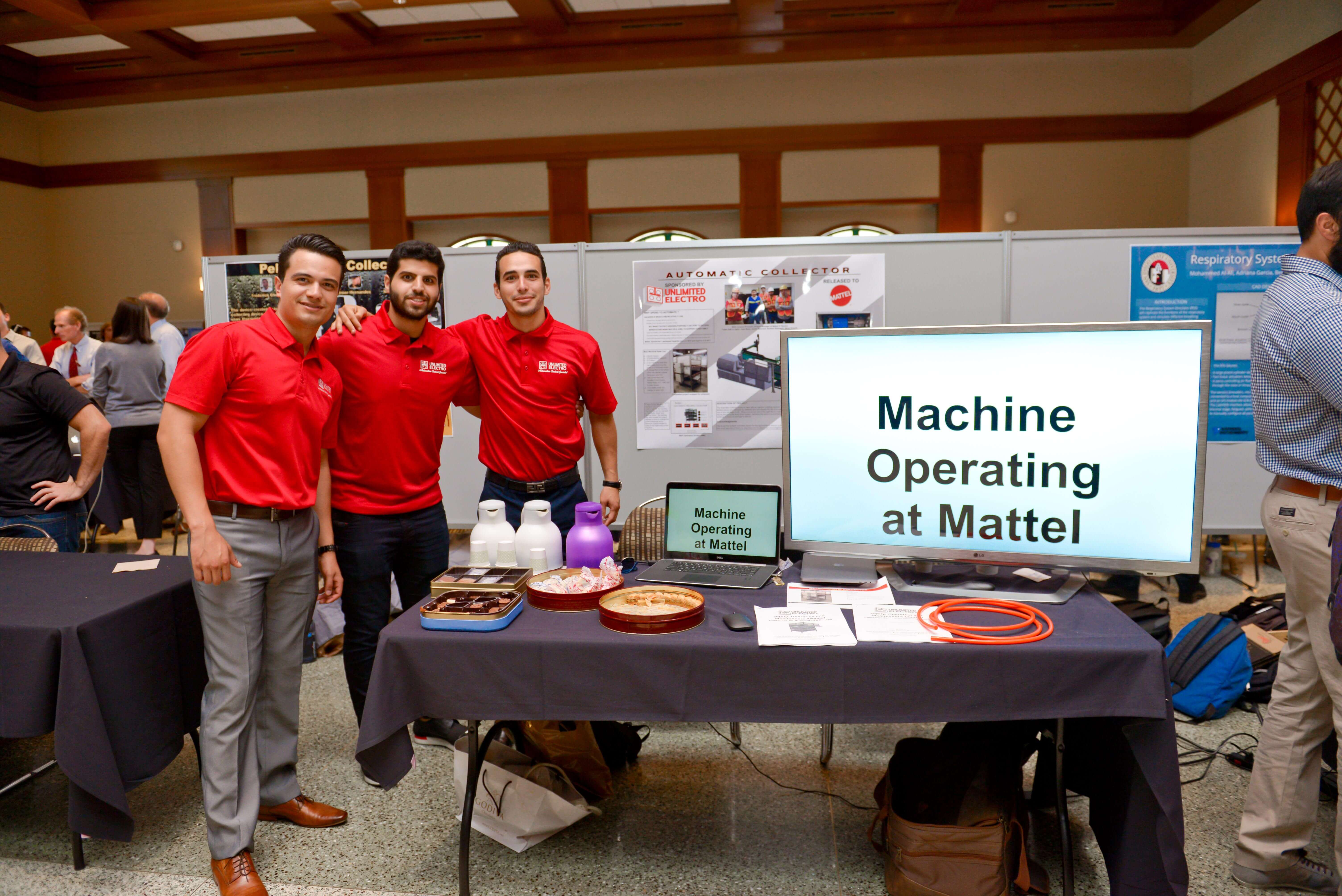 Three students standing behind table showing their project.