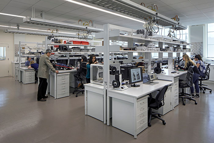 A modern electronics research laboratory in the Engineering & Interdisciplinary Sciences Complex with multiple workstations, occupied by students working on various class projects.