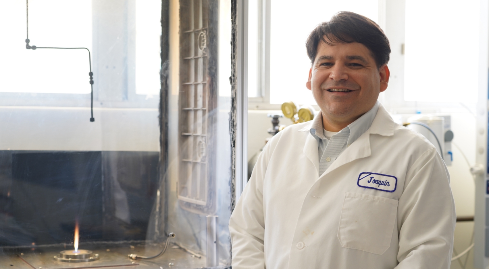 Joaquin Camacho, in his Engineering lab, shows the flame he uses to study the formation of carbon particles under different conditions. (Photo: Christopher Leap)